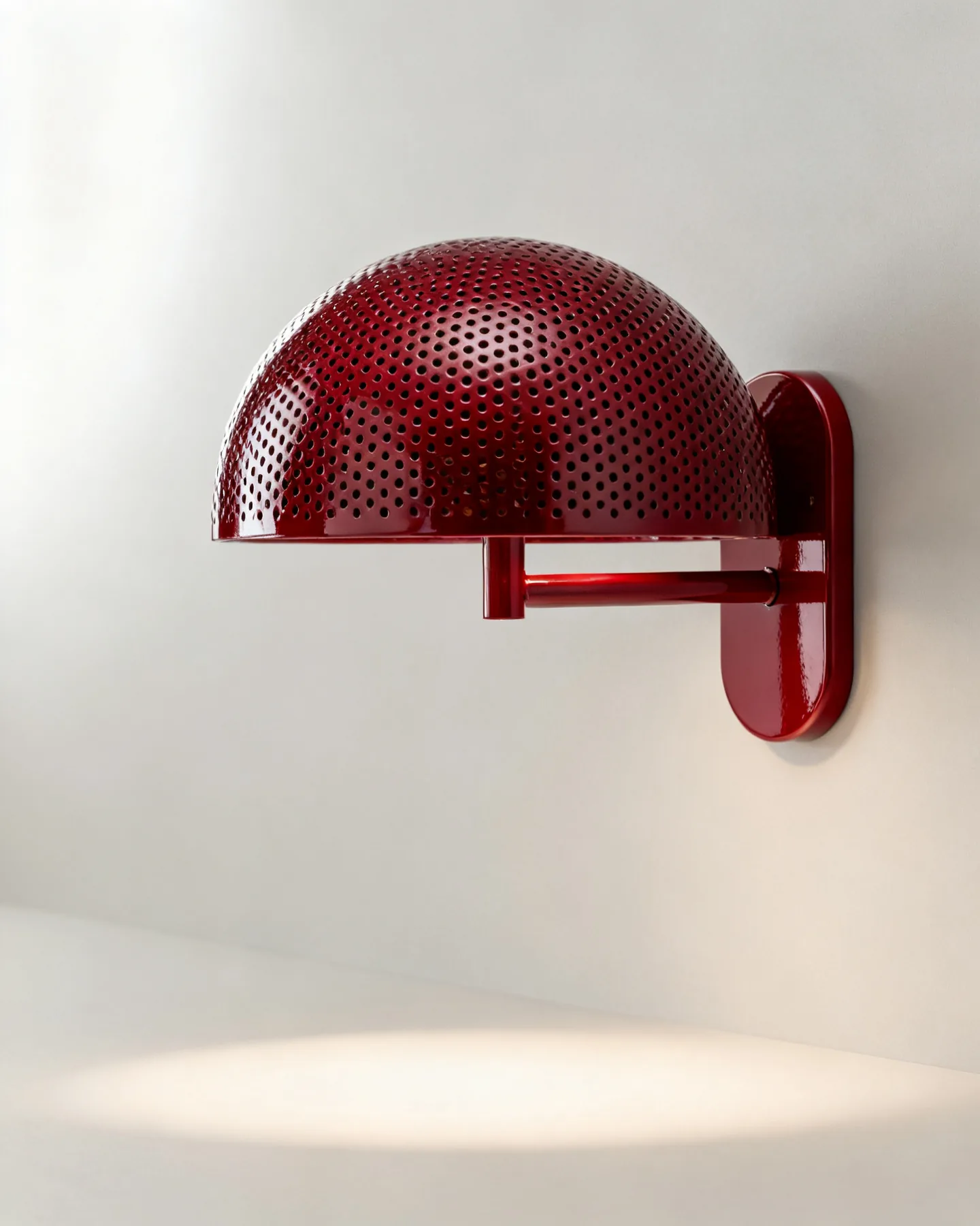 The Brogue wall light in racing red lacquer, its spun dome drilled with a field of fine perforations